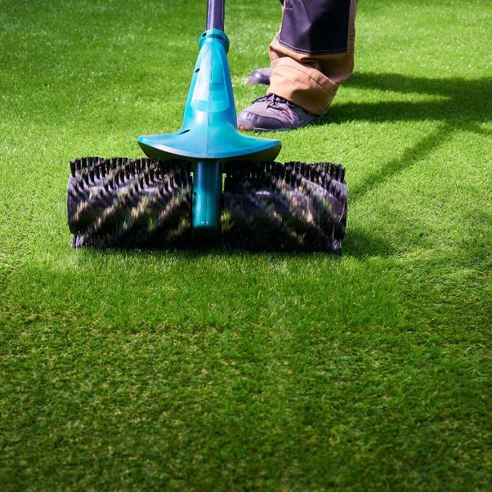 cleaning artificial grass with a brush