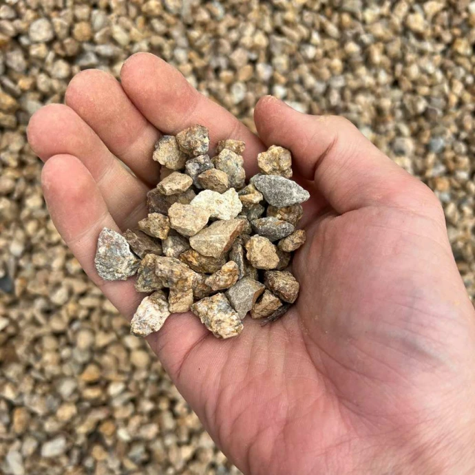 Hand displaying brown granite screenings (10-14mm)
